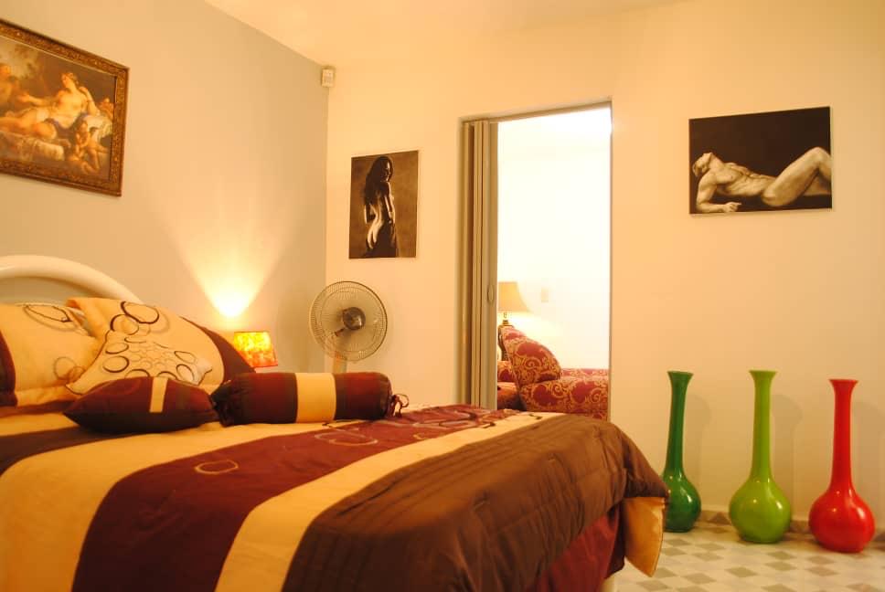 Classic room with a queen bed, framed art, green and red glass vases on a checkered floor