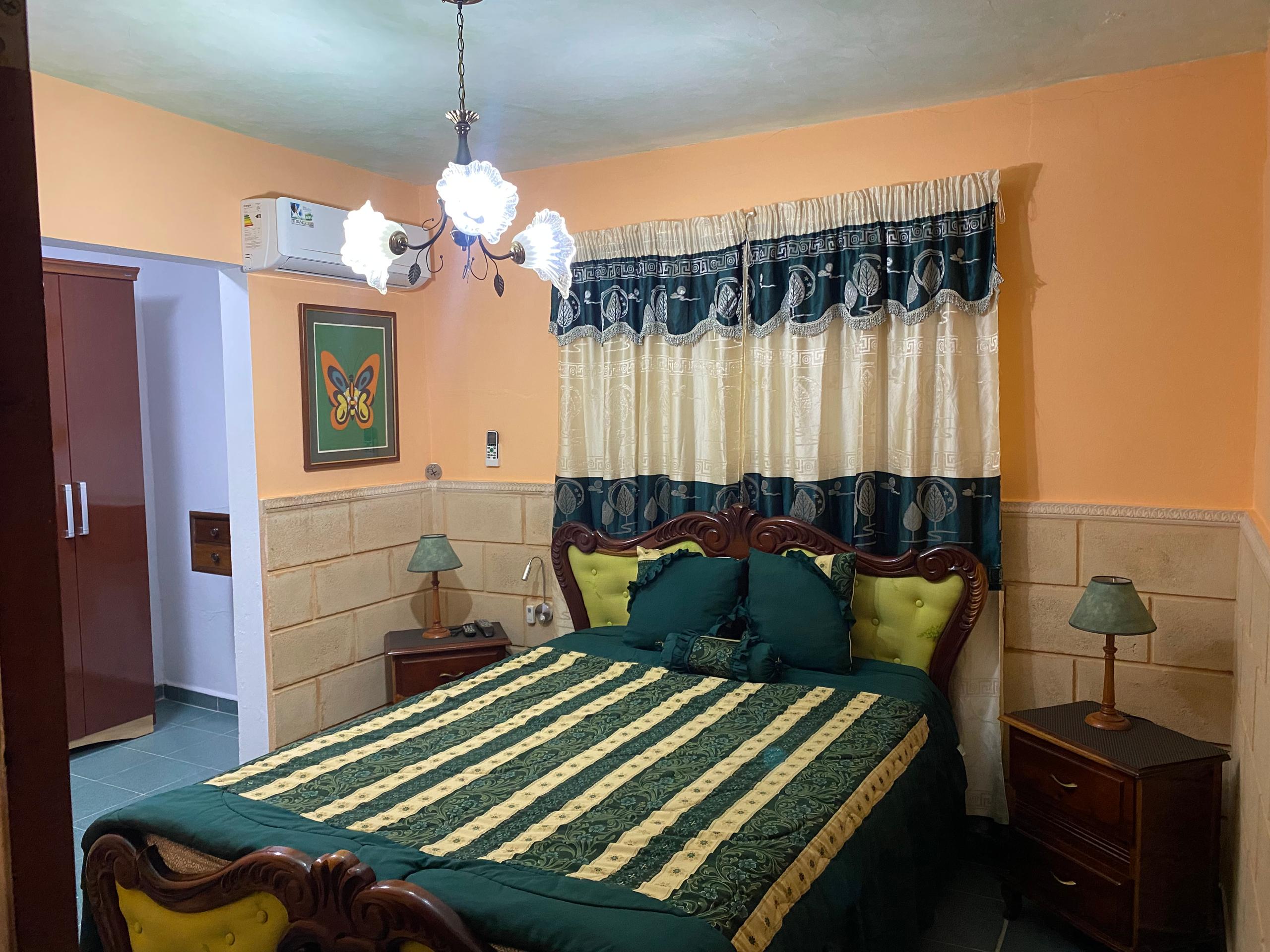 Amber-walled room with a carved mahogany bed, butterfly painting and chandelier