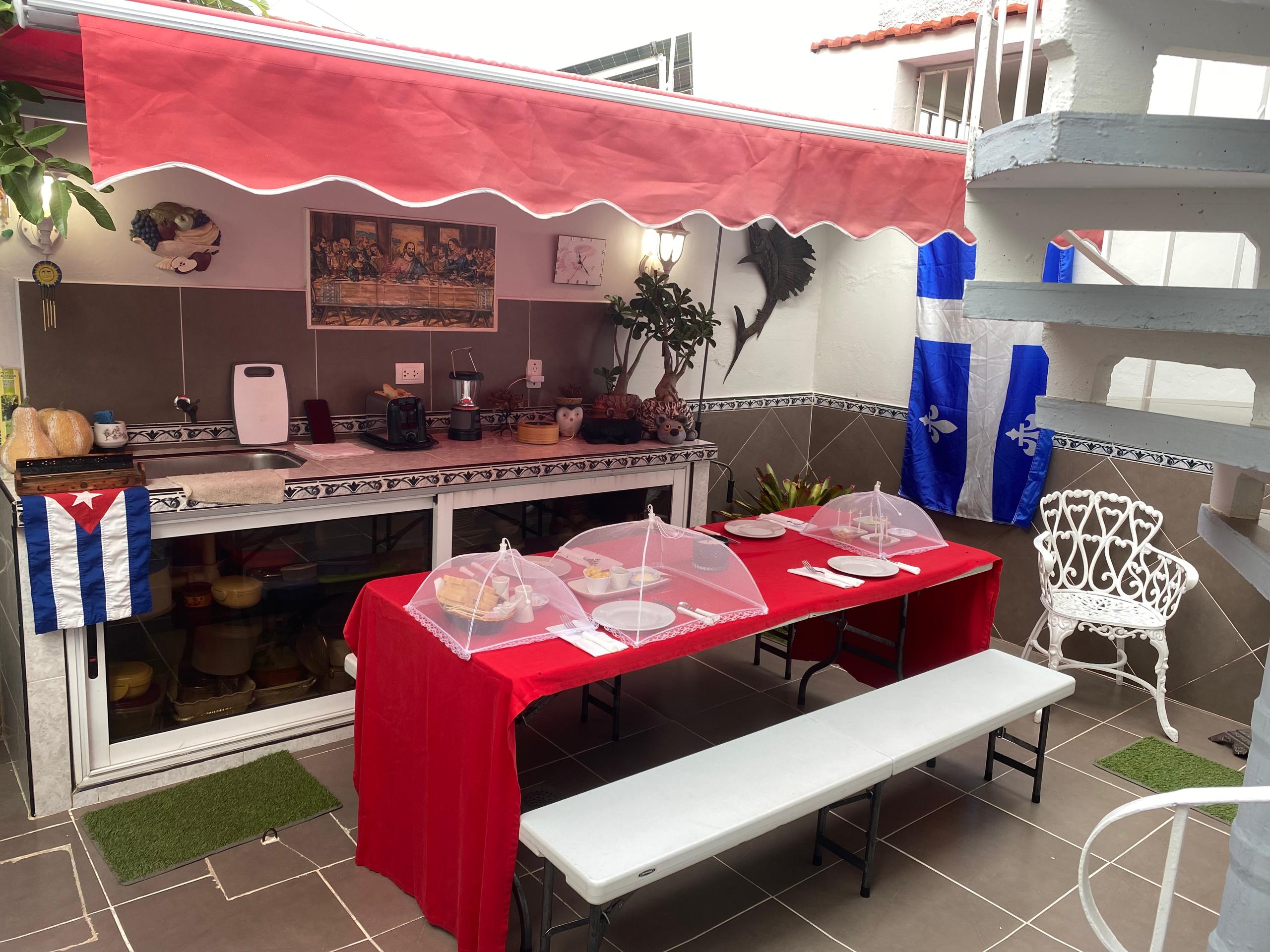 Outdoor kitchen on the terrace with a Cuban flag and a Last Supper print above